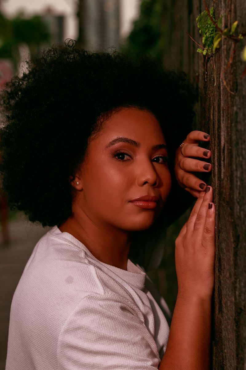 Close-up portrait of a woman leaning on a textured wall in Campina Grande, Brazil.